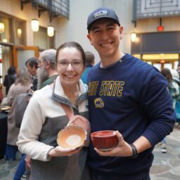 white man and woman standing together, each holding a bowl