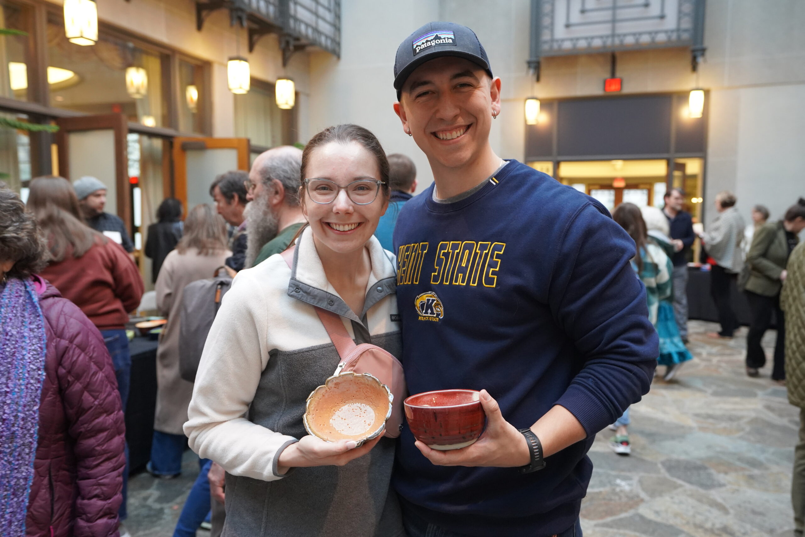 white man and woman standing together, each holding a bowl
