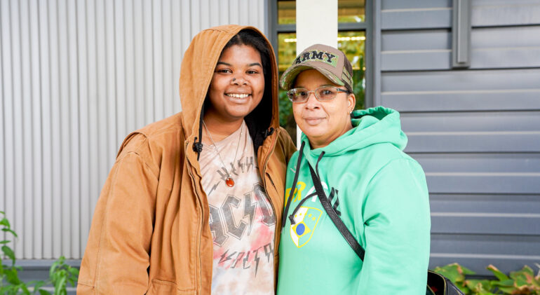 2 black women smiling wearing a brown and green jacket