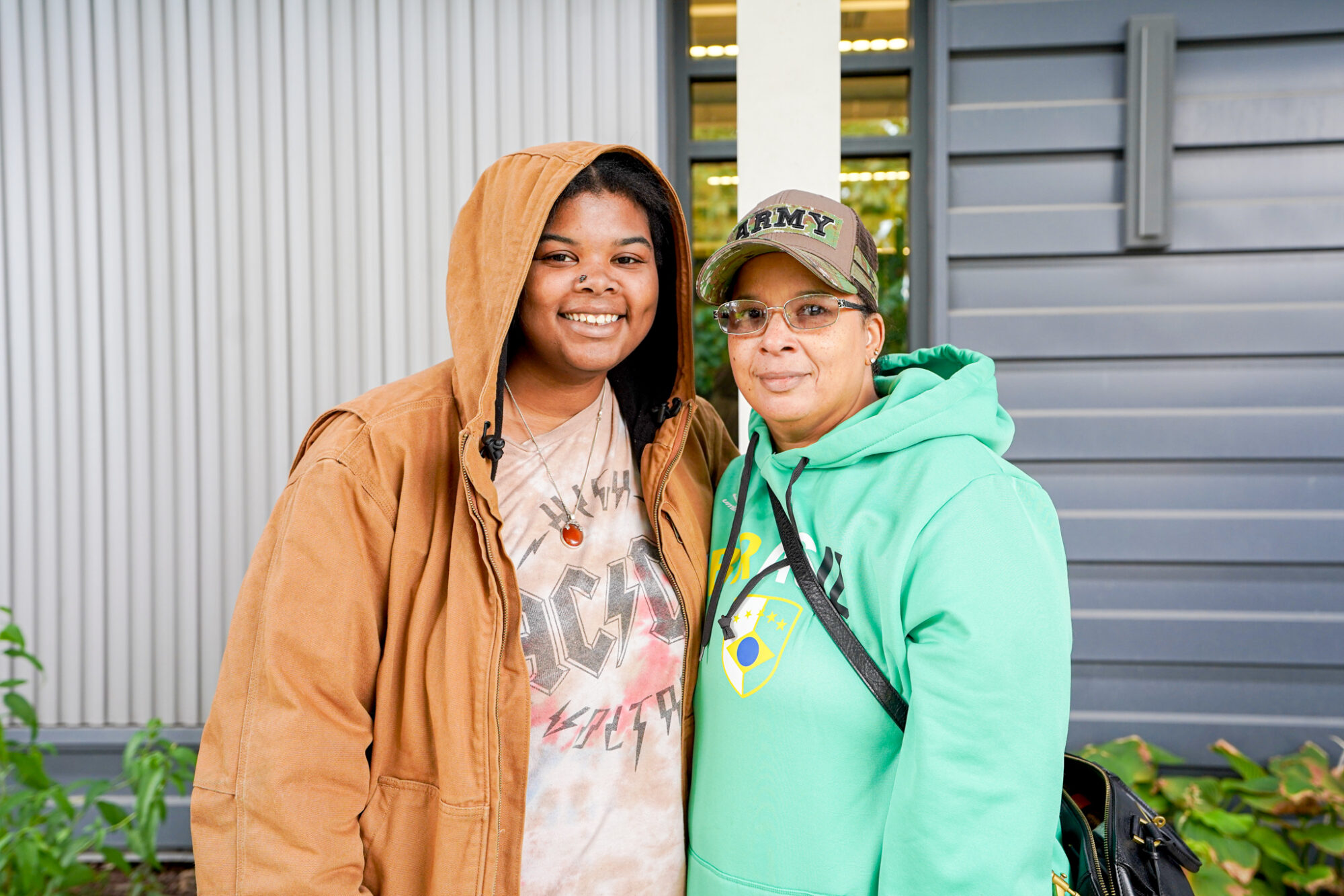 2 black women smiling wearing a brown and green jacket