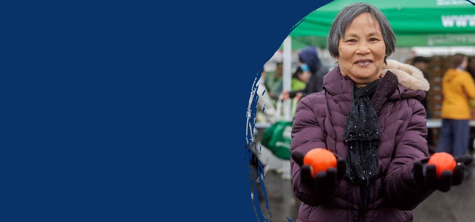 lady holding tomatoes in a purple jacket