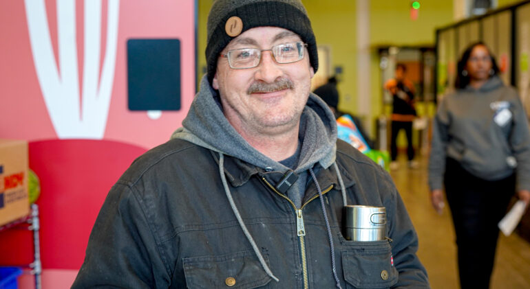 White man smiling wearing a grey jacket and grey beanie