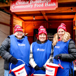 3 white women smiling wearing blue bibs, holding red buckets