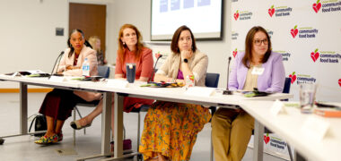 Group of women sitting at a white table with microphones